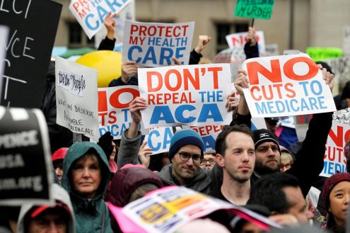 Demonstrators hold signs in support of the Affordable Care Act at a gathering before the start of a protest march near the hotel where House and Senate Republicans are attending a retreat, in Philadelphia